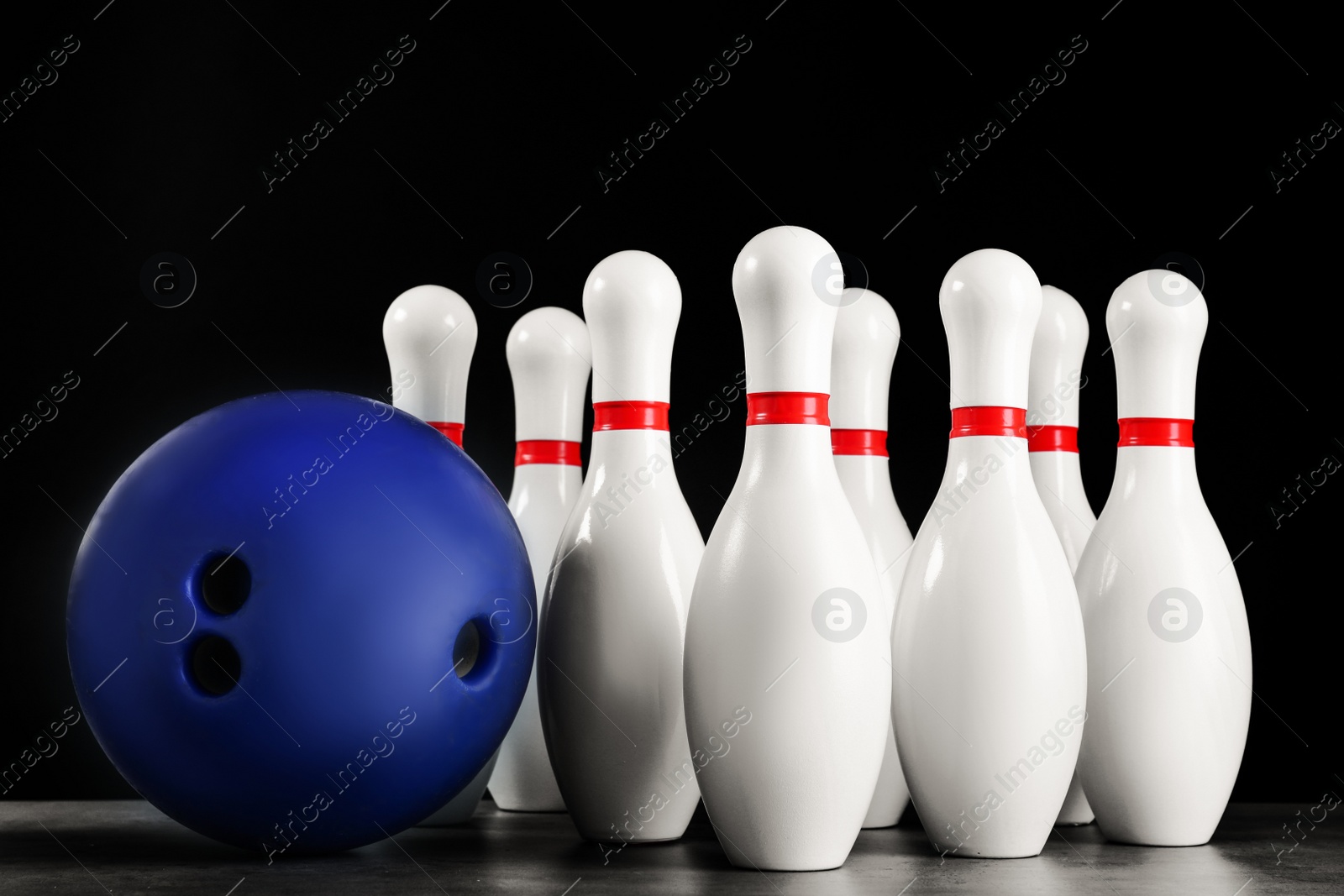 Photo of Blue bowling ball and pins on grey stone table