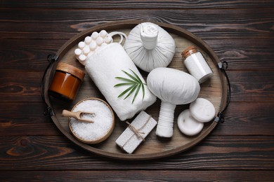 Composition of herbal bags and spa products on wooden table, top view