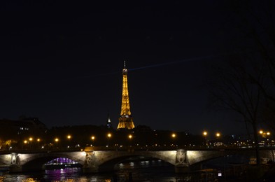 Paris, France - December 10, 2022: Picturesque view of city, Pont d'Iéna bridge and illuminated Eiffel Tower at night