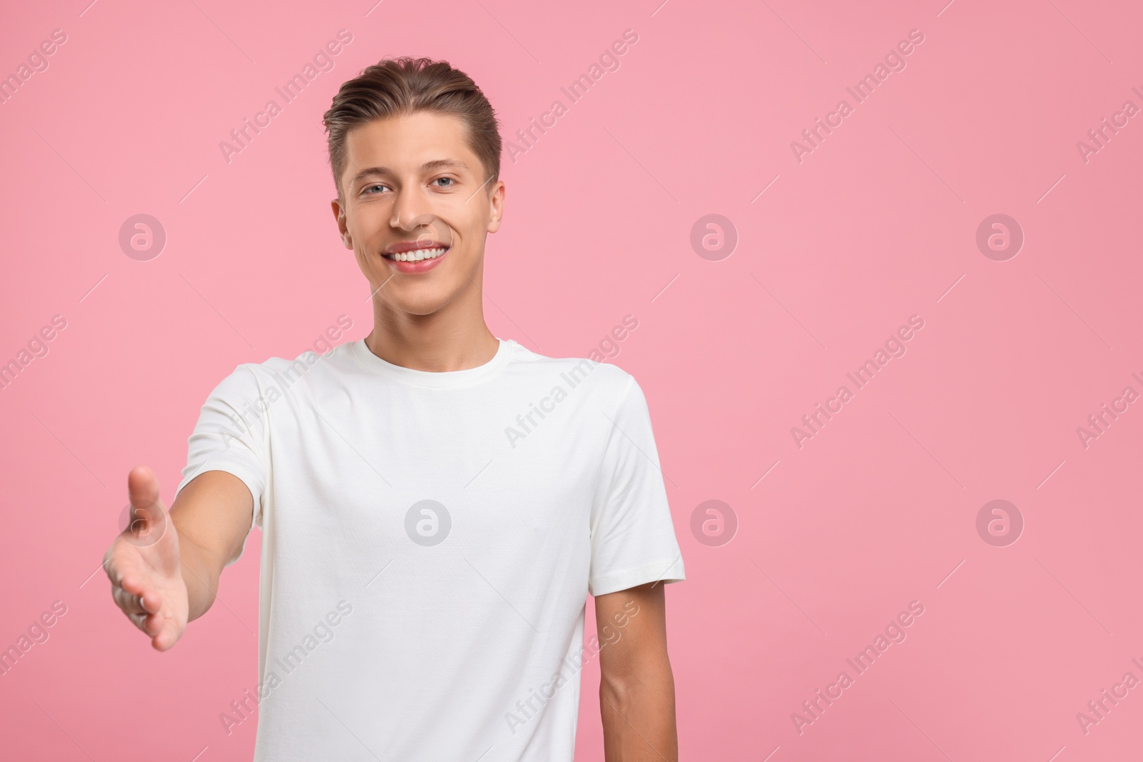 Photo of Happy man welcoming and offering handshake on pink background. Space for text