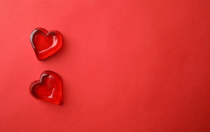 Photo of Sweet heart shaped jelly candies on red background, flat lay. Space for text