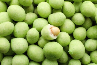 Tasty wasabi coated peanuts as background, top view