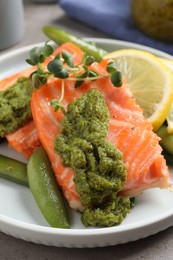 Photo of Tasty cooked salmon with pesto sauce on grey table, closeup