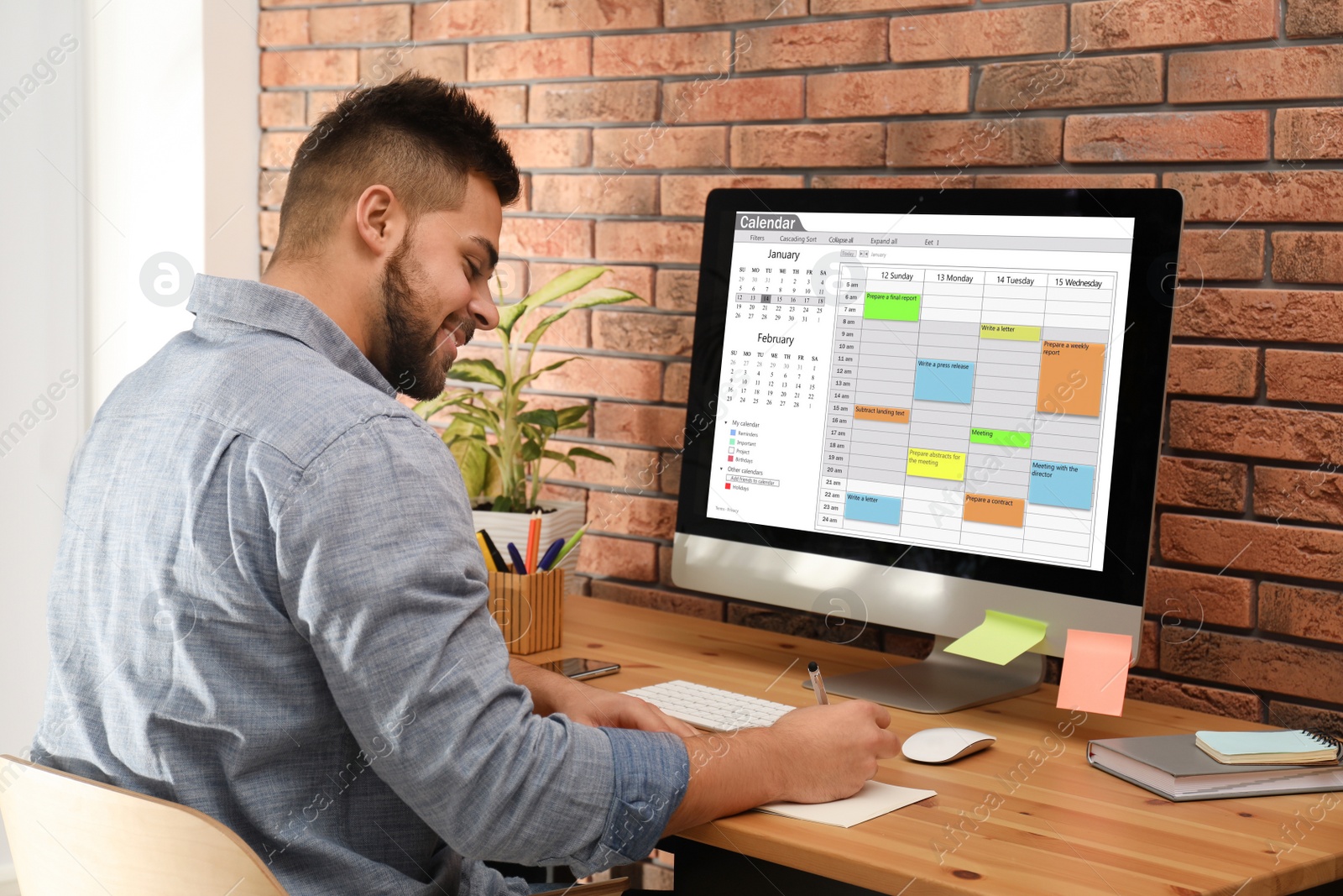 Photo of Young man using calendar app on computer in office