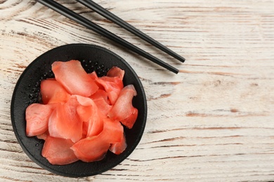 Photo of Spicy pickled ginger and chopsticks on white wooden table, flat lay. Space for text