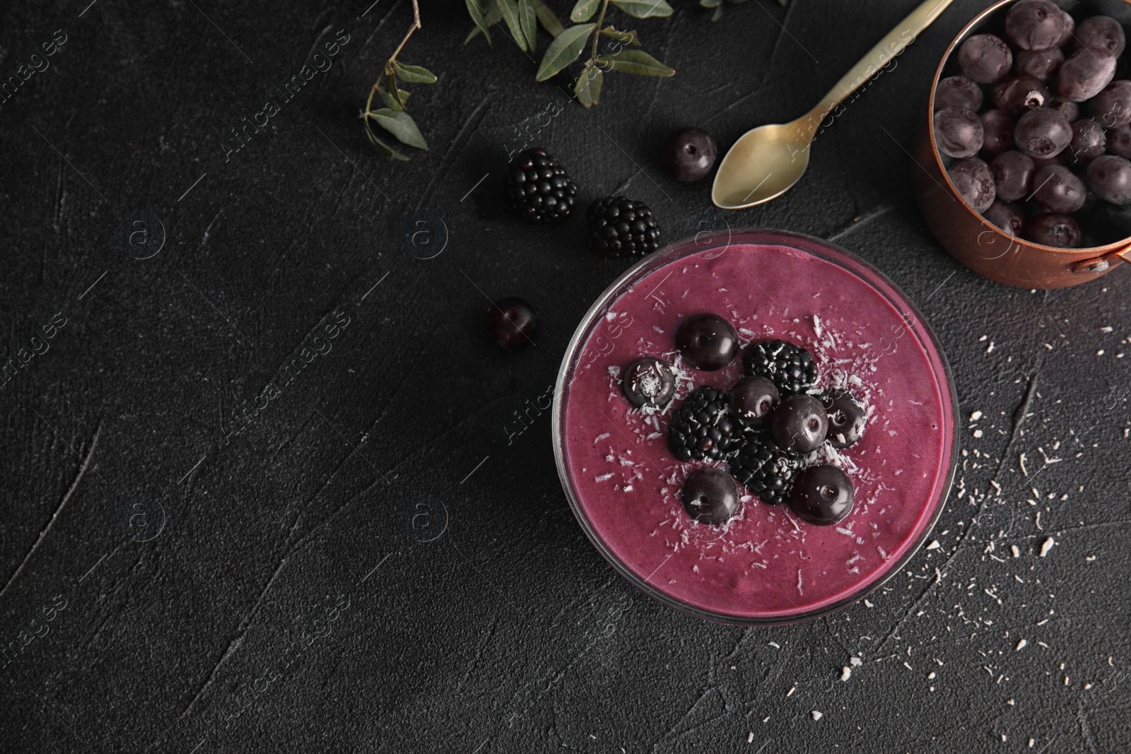 Photo of Flat lay composition with bowl of tasty acai smoothie on dark table