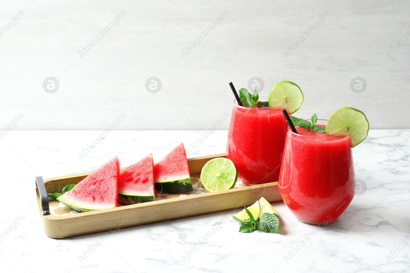 Photo of Summer watermelon drink in glasses and sliced fruits on table