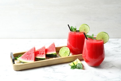 Photo of Summer watermelon drink in glasses and sliced fruits on table