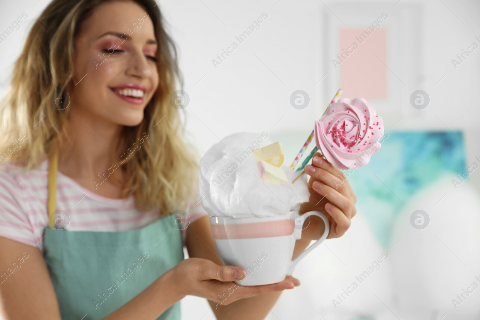 Photo of Young woman with cup of cotton candy dessert indoors