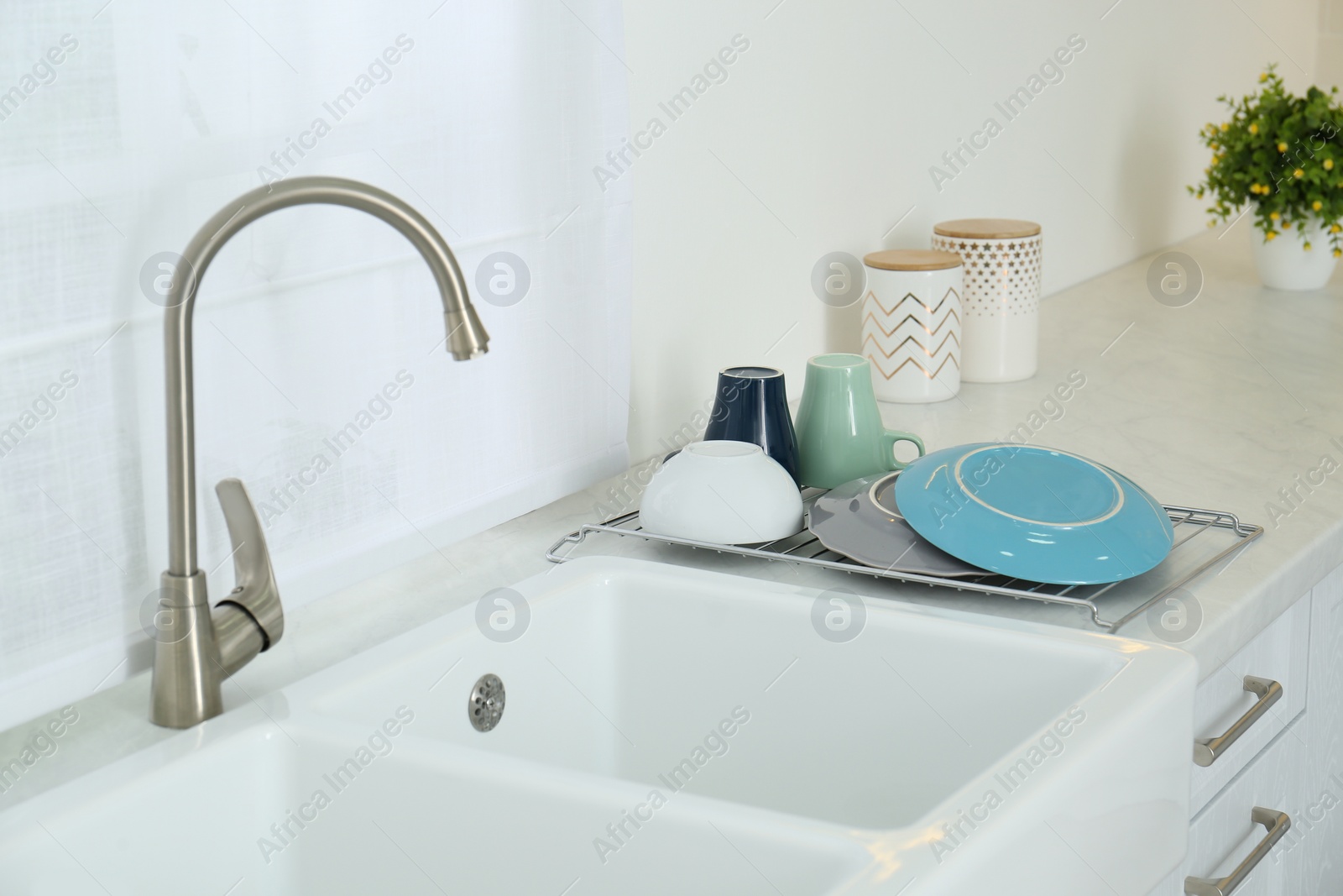Photo of Clean dishes drying on rack in modern kitchen