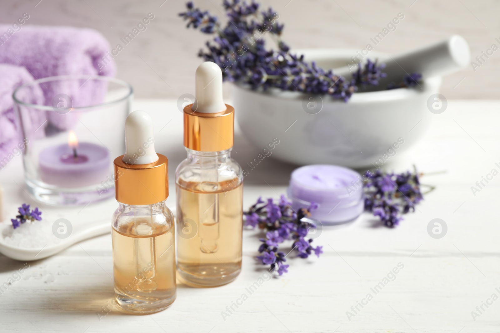 Photo of Composition with bottles of essential oil and lavender flowers on white wooden table