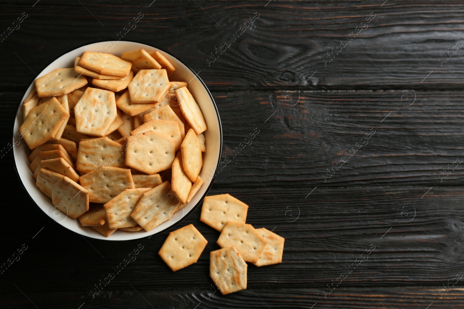 Photo of Delicious crackers on black wooden table, flat lay. Space for text
