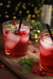 Photo of Tasty refreshing cranberry cocktail with mint on wooden table, closeup