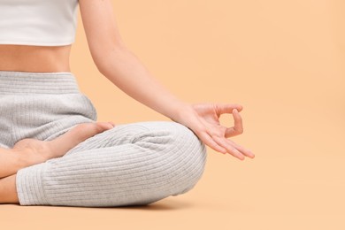 Woman practicing yoga on beige background, closeup and space for text. Lotus pose