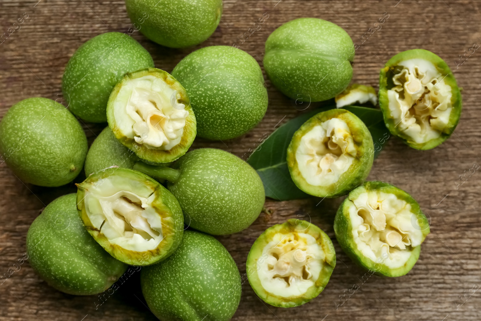 Photo of Whole and broken green walnuts on wooden table, flat lay