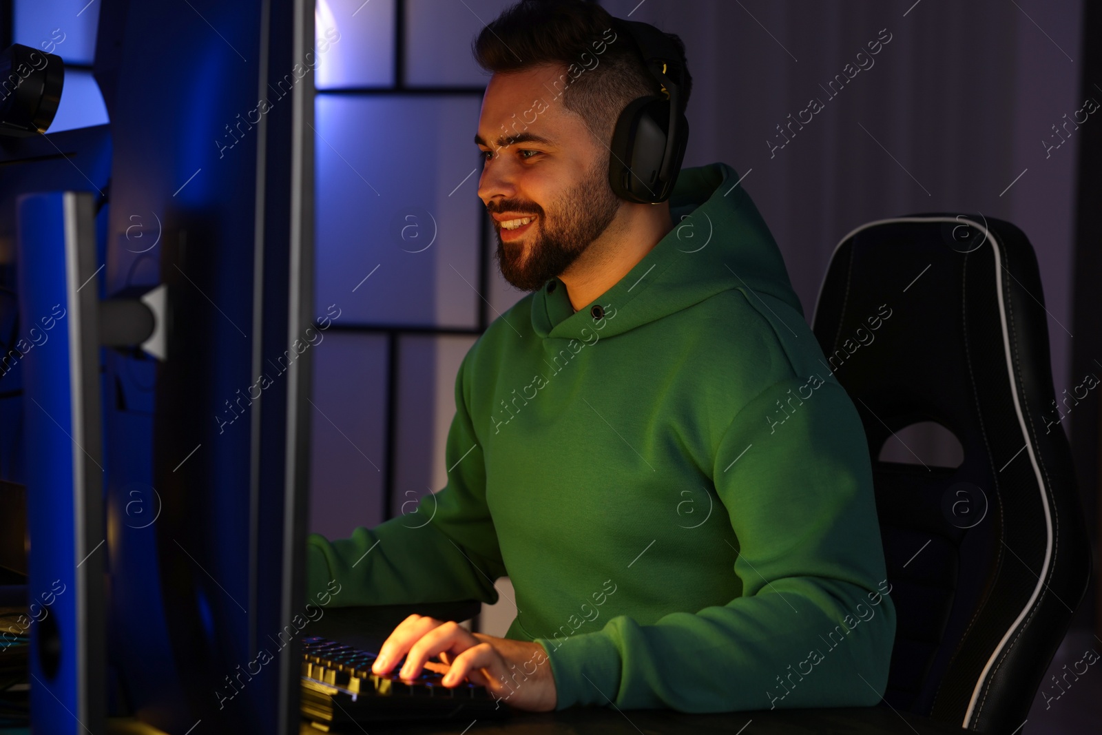 Photo of Man playing video games on computer at table indoors