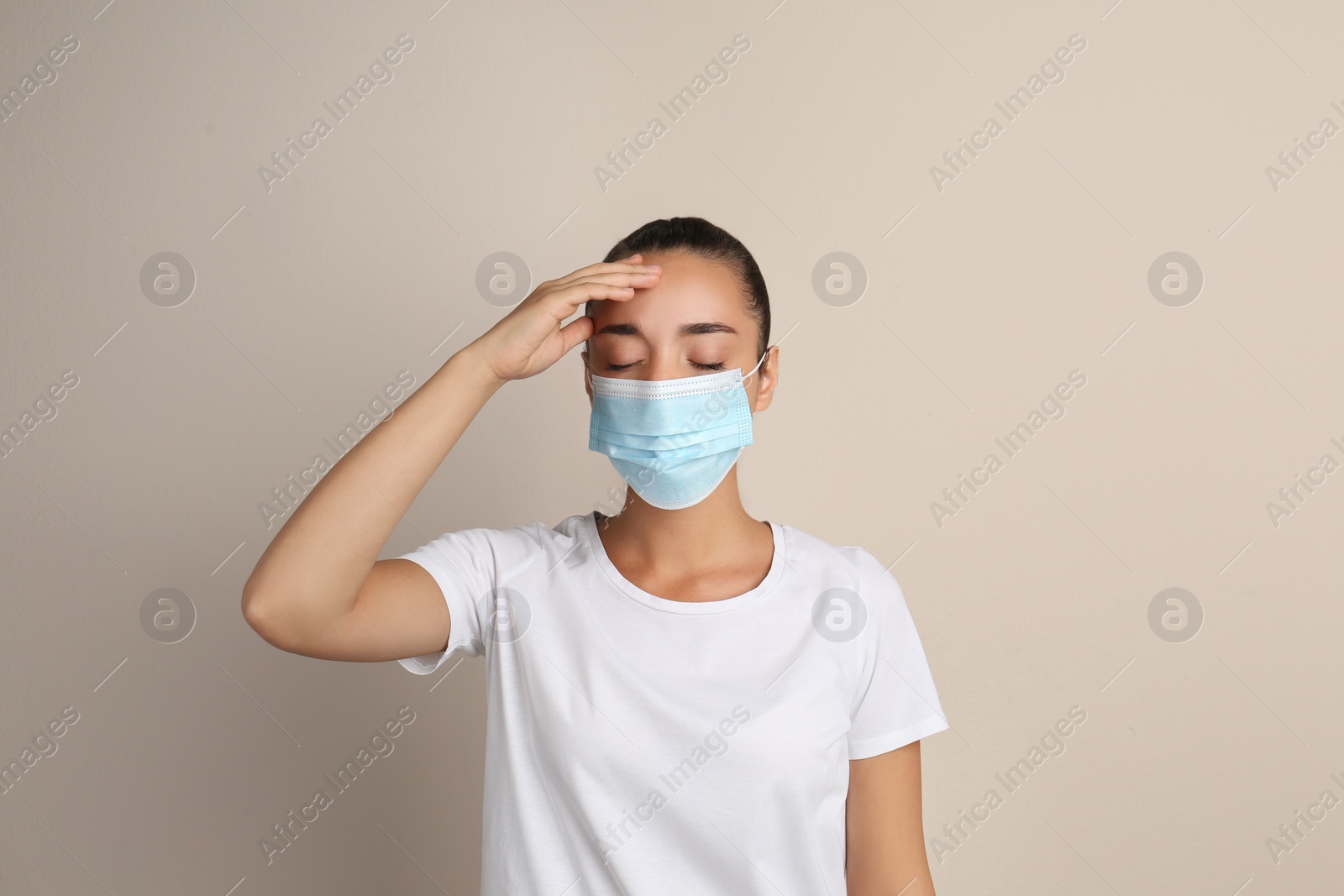 Photo of Stressed woman in protective mask on beige background. Mental health problems during COVID-19 pandemic