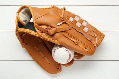 Photo of Leather baseball glove with ball on white wooden table, top view