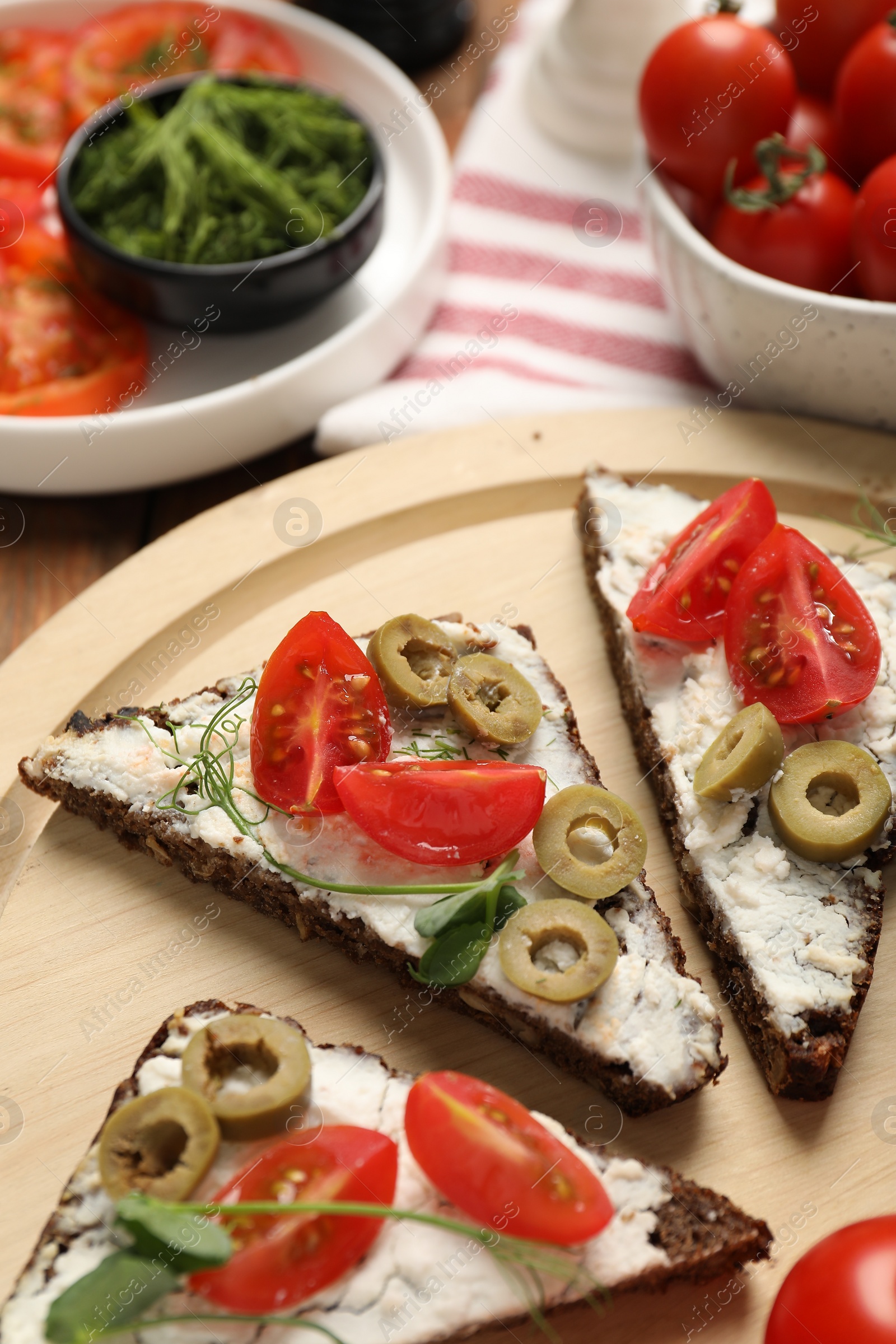 Photo of Delicious ricotta bruschettas with fresh tomatoes, olives and greens on table