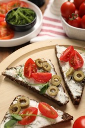Photo of Delicious ricotta bruschettas with fresh tomatoes, olives and greens on table
