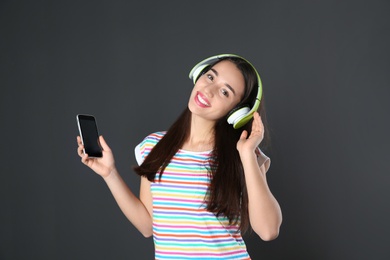 Beautiful young woman listening to music with headphones on black background