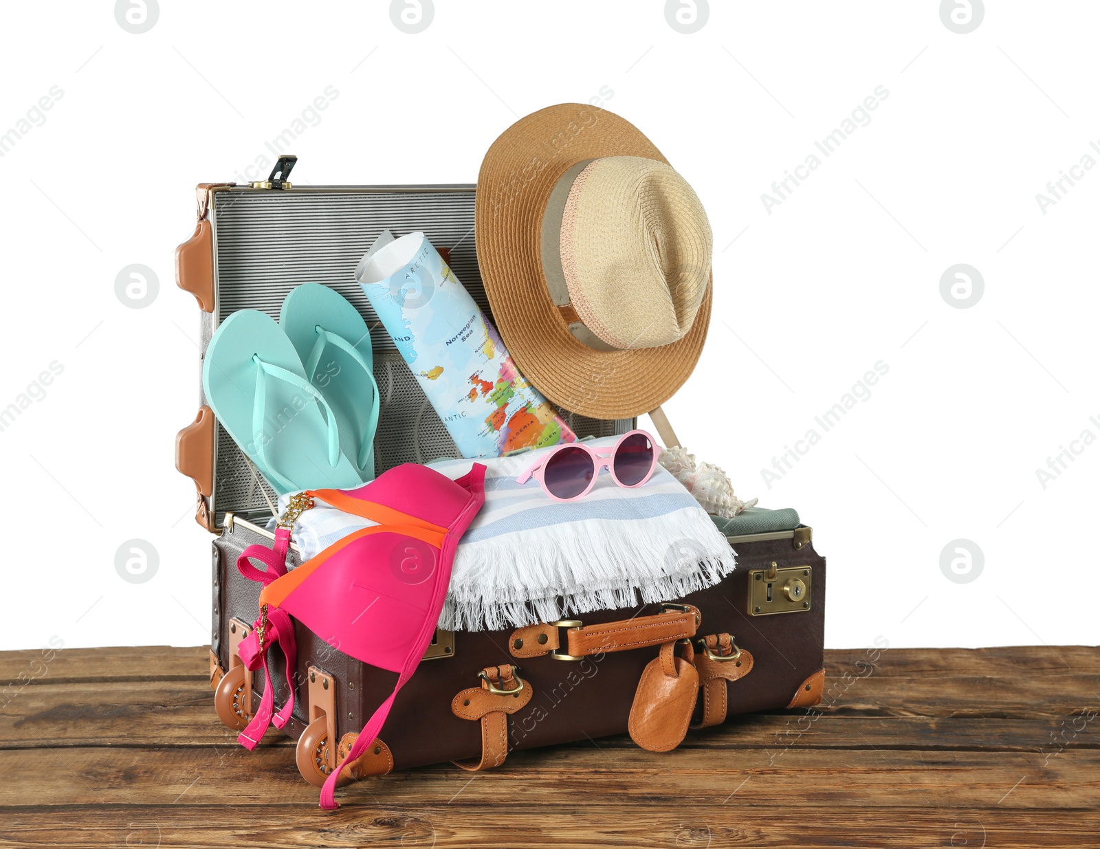 Photo of Open vintage suitcase with different beach objects packed for summer vacation on wooden table against white background