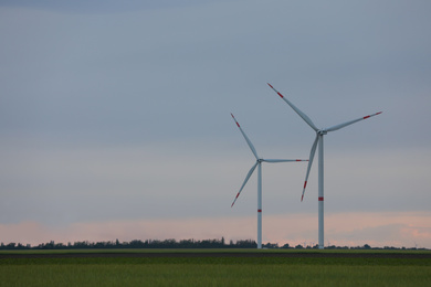 Photo of Beautiful view of field with wind turbines in evening. Alternative energy source