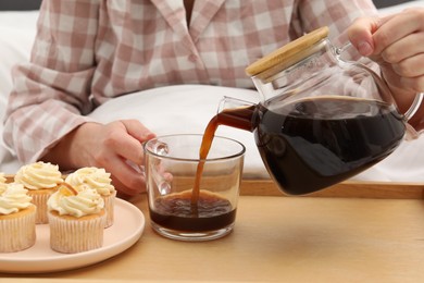 Photo of Woman pouring hot drink into cup in bed, closeup