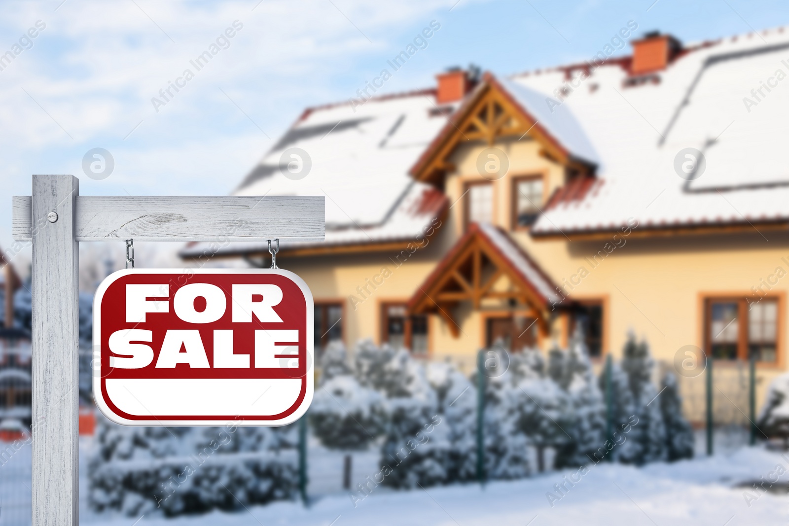 Image of Sale sign near beautiful house outdoors in winter. Red signboard with words