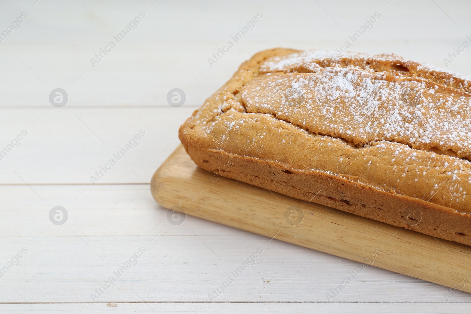 Photo of Delicious homemade yogurt cake with powdered sugar on white wooden table, closeup