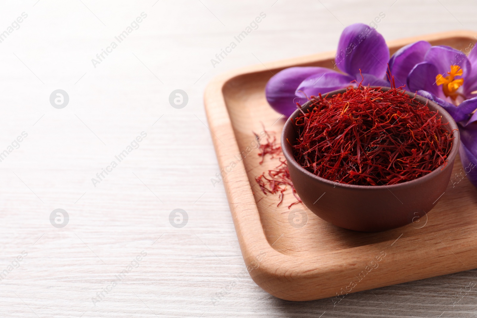 Photo of Dried saffron and crocus flowers on white wooden table, space for text
