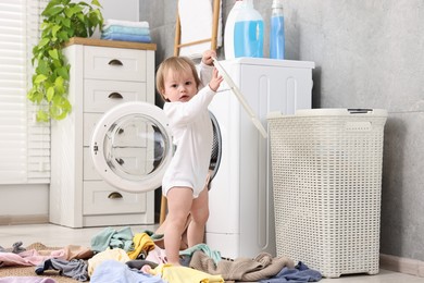 Photo of Little girl among baby clothes in bathroom