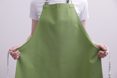 Photo of Woman putting on green apron against white background, closeup