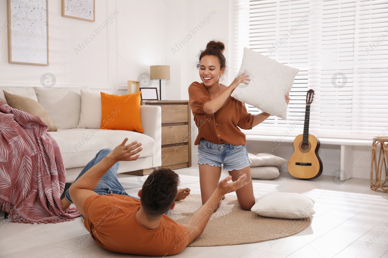 Photo of Happy couple having pillow fight in living room