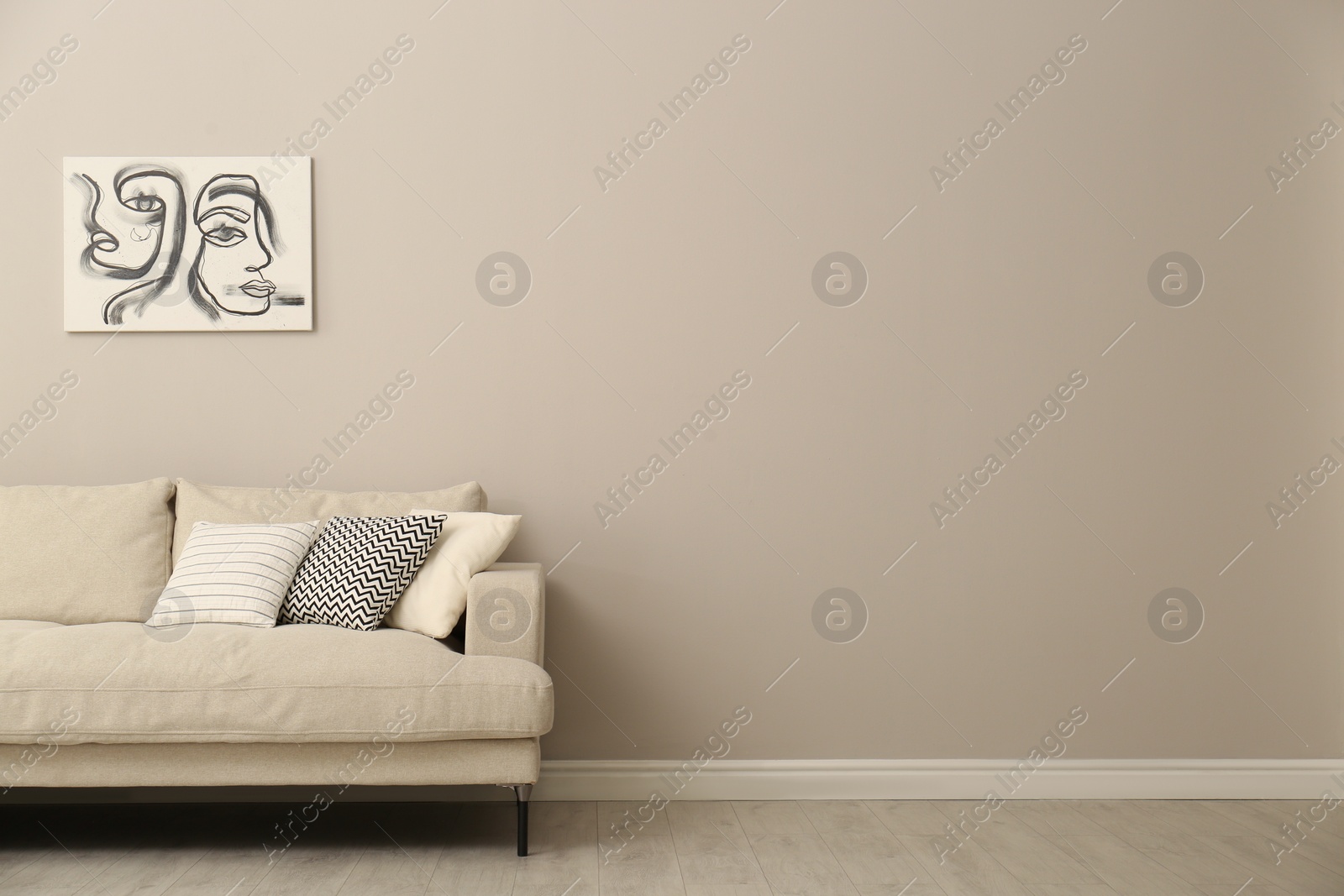 Photo of Modern comfortable sofa and picture near wall in room. Interior design