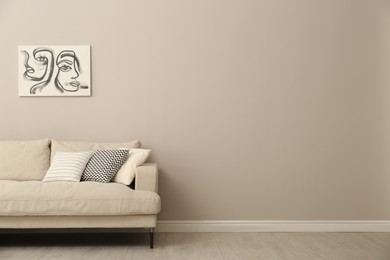 Photo of Modern comfortable sofa and picture near wall in room. Interior design