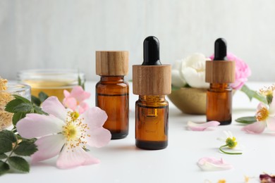 Photo of Aromatherapy. Essential oils and flowers on white table, closeup