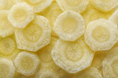 Pieces of raw white carrot as background, top view