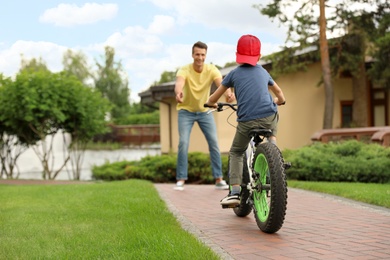 Dad teaching son to ride bicycle outdoors