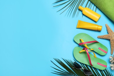 Photo of Stylish flip flops and beach objects on light blue background, flat lay. Space for text