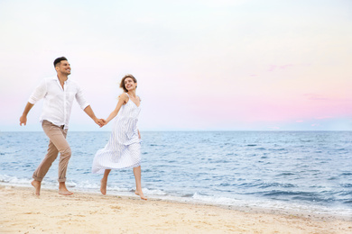 Happy couple having romantic walk on beach. Space for text