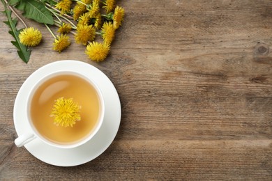 Photo of Delicious tea and dandelion flowers on wooden table, flat lay. Space for text