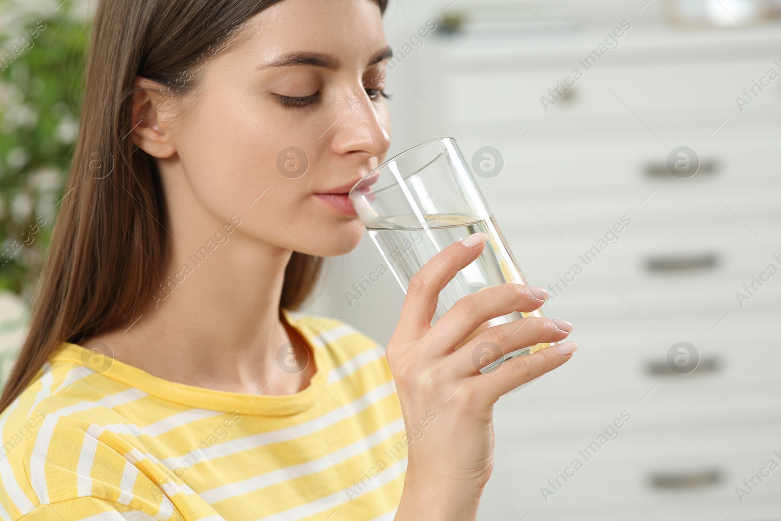 Photo of Healthy habit. Woman drinking fresh water from glass indoors