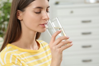 Photo of Healthy habit. Woman drinking fresh water from glass indoors