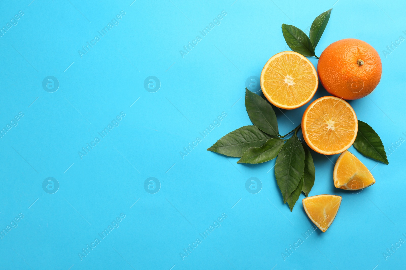 Photo of Delicious oranges on light blue background, flat lay. Space for text