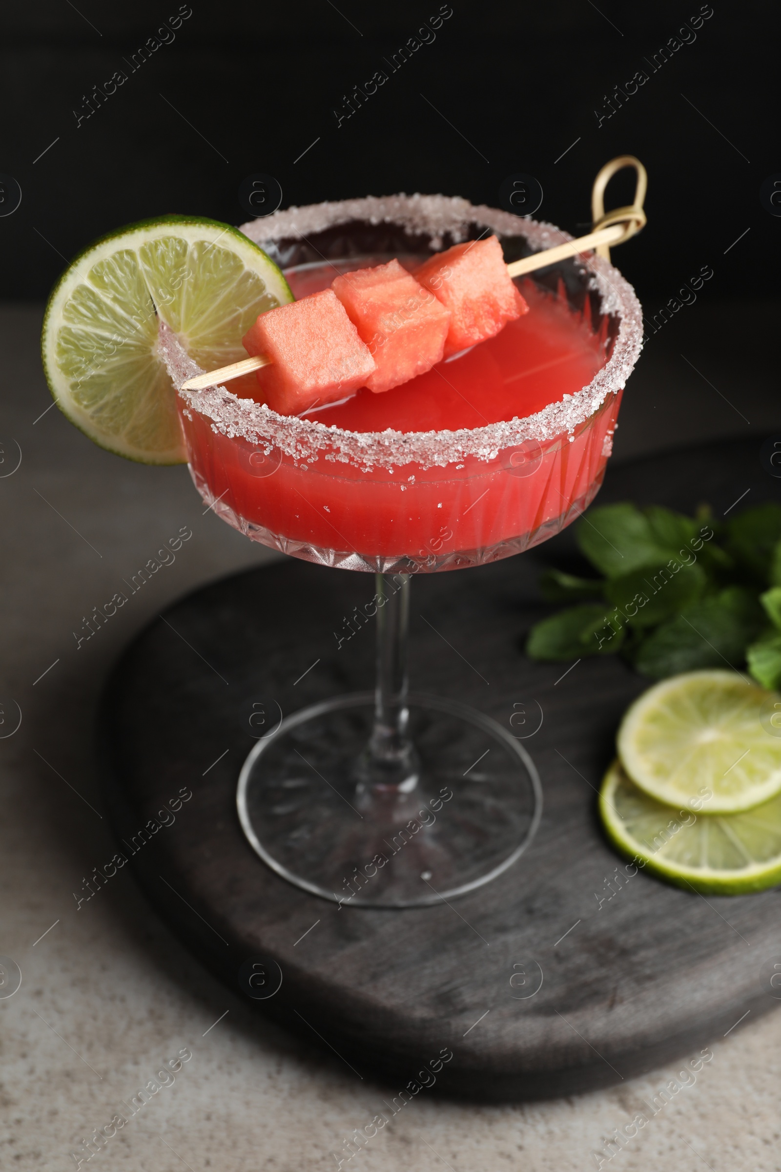 Photo of Cocktail glass of delicious fresh watermelon juice, lime and mint on grey table