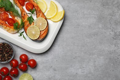 Photo of Tasty grilled salmon steaks and ingredients on light grey table, flat lay. Space for text