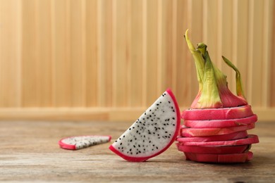 Slices of delicious dragon fruit (pitahaya) on wooden table. Space for text