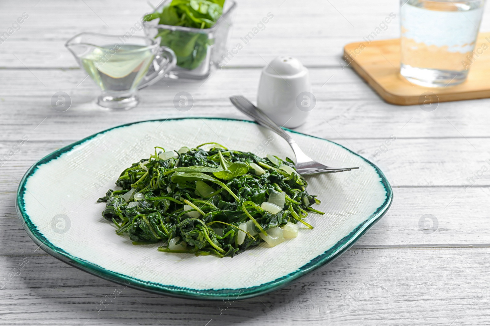 Photo of Tasty cooked spinach served on white wooden table. Healthy food