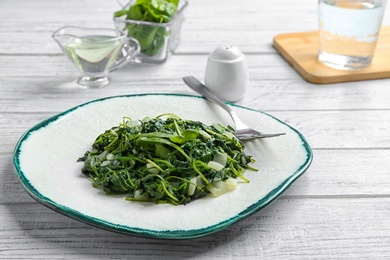 Photo of Tasty cooked spinach served on white wooden table. Healthy food